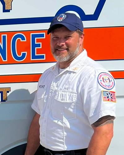 Paramedic in uniform standing in front of an ambulance.