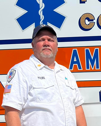 Paramedic standing confidently in front of an ambulance.